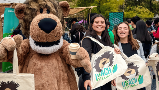 Estudiantes de la Usach mostrando los regalos institucionales junto a Usachín (mascota institucional) por su participación en la Feria Usach Sostenible 2025.